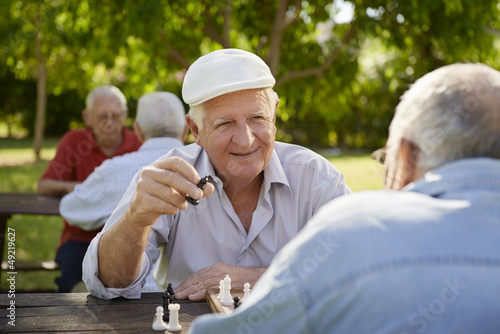 Photo: Active retired seniors, two old men playing chess at park Active retired seniors, two old men playing chess at park