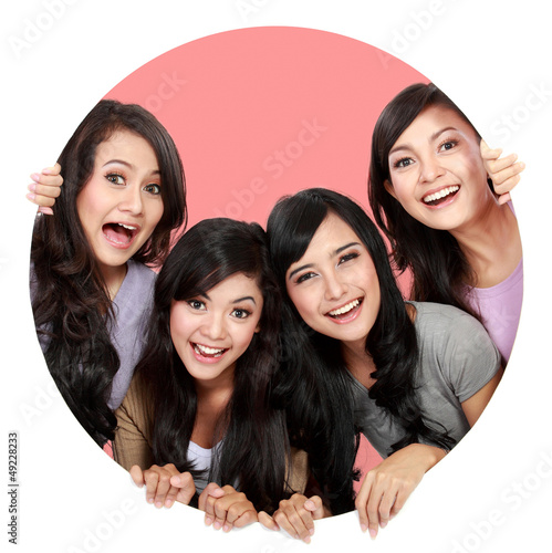 Photo: Group of beautiful women smiling peeping through circle hole Group of beautiful women smiling peeping through circle hole