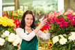Happy young woman arranging flowers florist shop