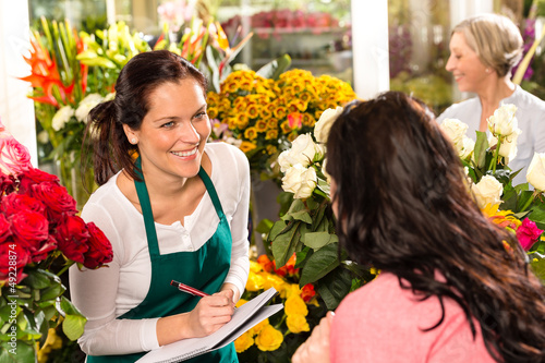 Photo: Happy florist writing flower shop talking customer Happy florist writing flower shop talking customer