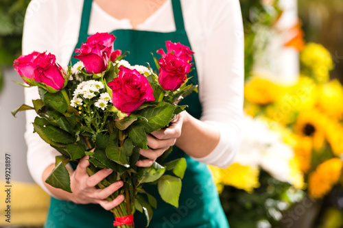 Photo: Florist hands showing red roses bouquet flowers Florist hands showing red roses bouquet flowers