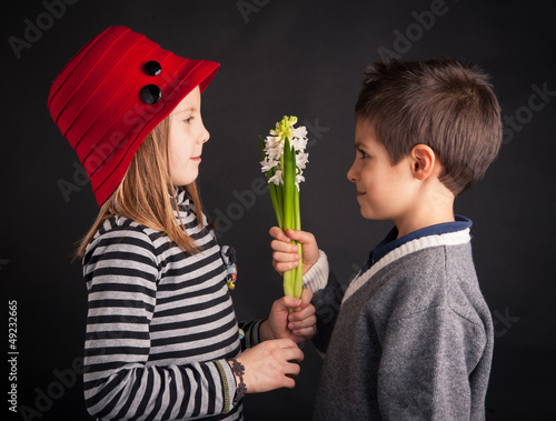 Photo: Boy offering flower on black background. Valentines day concept. Boy offering flower on black background. Valentines day concept.
