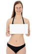 Junge Frau in schwarzem Bikini hält leeres Schild