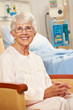 Portrait Of Senior Female Patient In Chair By Hospital Bed