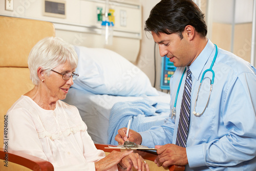 Photo: Doctor Taking Notes From Senior Female Patient Seated In Chair Doctor Taking Notes From Senior Female Patient Seated In Chair