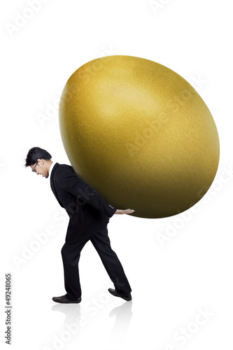 Photo: Businessman carry huge gold egg Businessman carry huge gold egg