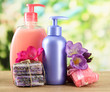 Liquid and hand-made soaps on wooden table, on green background