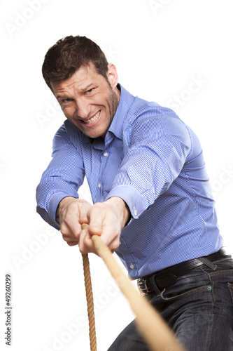 Photo: Young man pulling a rope on white background Young man pulling a rope on white background