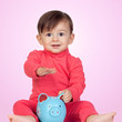 Adorable baby girl sitting with a blue piggy-bank