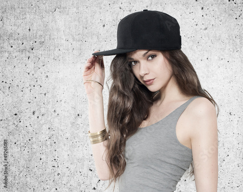 Photo: Beautiful young woman in fullcap on grey background Beautiful young woman in fullcap on grey background