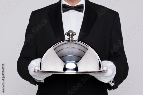 Photo: Waiter holding a silver cloche Waiter holding a silver cloche