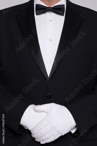 Photo: Man in a tuxedo wearing white gloves. Man in a tuxedo wearing white gloves.
