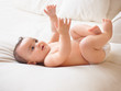 Shot of a cute baby reaching upwards while lying on a bed