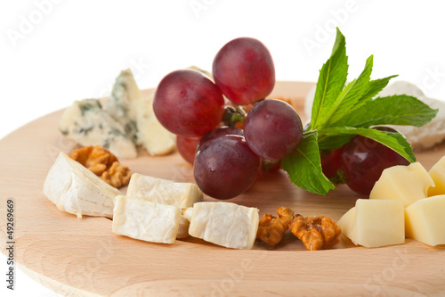 Photo: Various types of cheese with nuts and grapes on plate Various types of cheese with nuts and grapes on plate