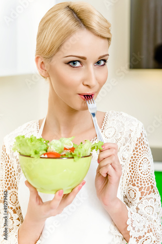 Photo: Portrait of a beautiful young woman eating vegetable salad Portrait of a beautiful young woman eating vegetable salad