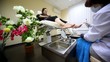 Young woman sits in armchair for pedicure near to flowers