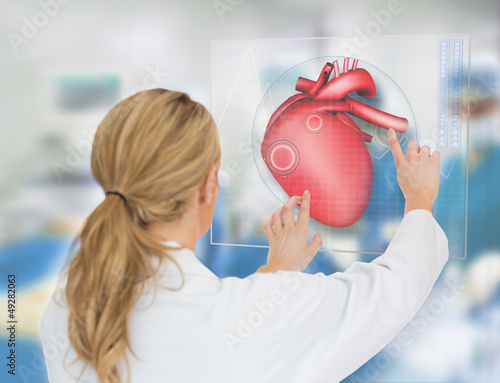 Photo: Blonde doctor consulting touchscreen displaying heart diagram Blonde doctor consulting touchscreen displaying heart diagram