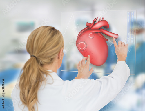 Photo: Blonde doctor consulting heart diagram on touchscreen display Blonde doctor consulting heart diagram on touchscreen display