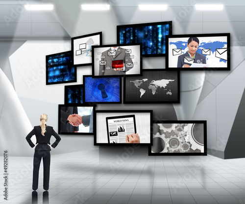 Photo: Businesswoman looking up at screens Businesswoman looking up at screens