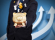 Businessman holding a piggy bank with currencies