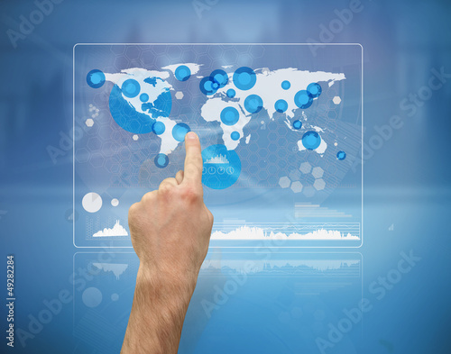 Photo: Hand pointing a futuristic screen with the world map Hand pointing a futuristic screen with the world map