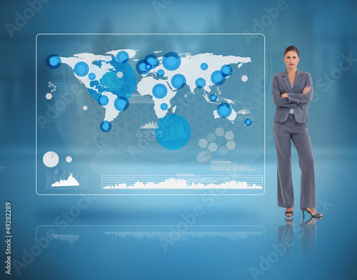 Photo: Stern businesswoman standing against a futuristic screen Stern businesswoman standing against a futuristic screen