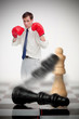Photo: Businessman in boxing gloves knocking over chess pieces Businessman in boxing gloves knocking over chess pieces
