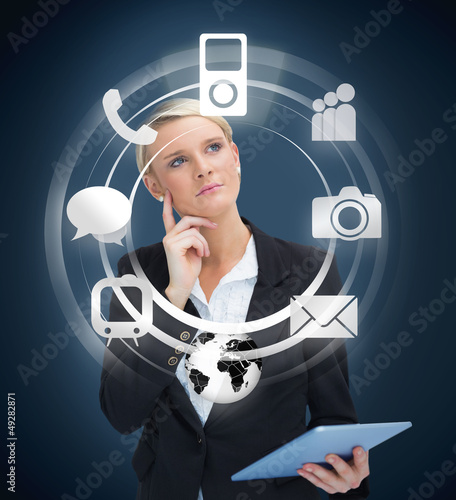 Photo: Thoughtful businesswoman with tablet pc considering various appl Thoughtful businesswoman with tablet pc considering various appl
