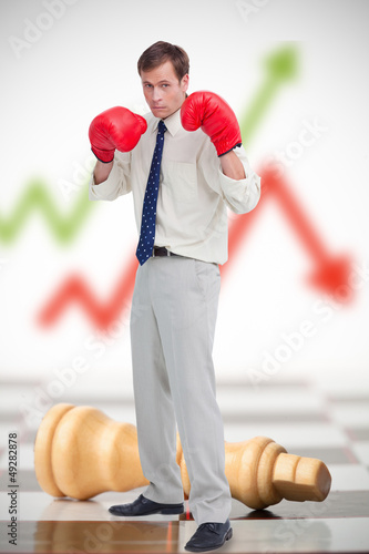 Photo: Businessman in boxing gloves on chessboard Businessman in boxing gloves on chessboard