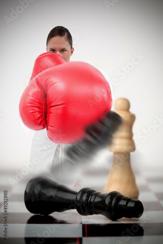 Photo: Woman in boxing gloves knocking over chess pieces Woman in boxing gloves knocking over chess pieces