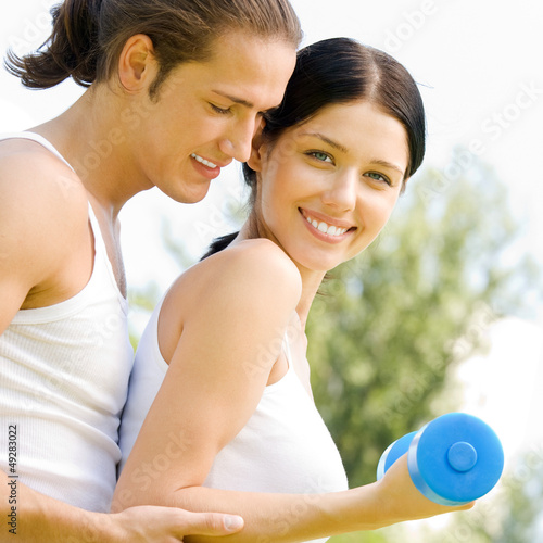 Photo: Cheerful couple with dumbbells on workout Cheerful couple with dumbbells on workout