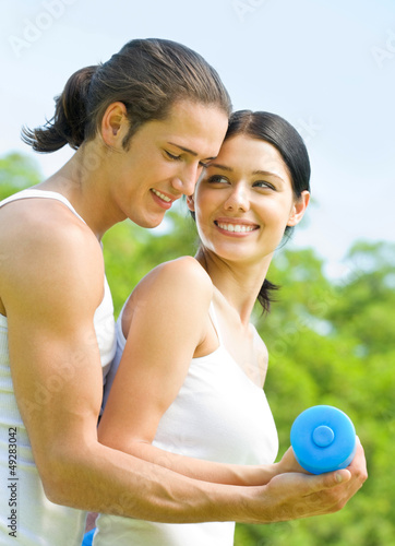 Photo: Cheerful couple with dumbbells on workout Cheerful couple with dumbbells on workout