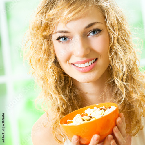 Photo: Cheerful woman eating cereal muslin Cheerful woman eating cereal muslin