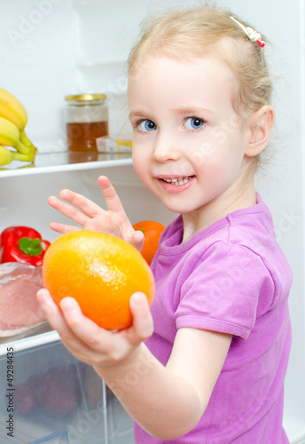 Photo: Happy smiling little girl holding orange Happy smiling little girl holding orange