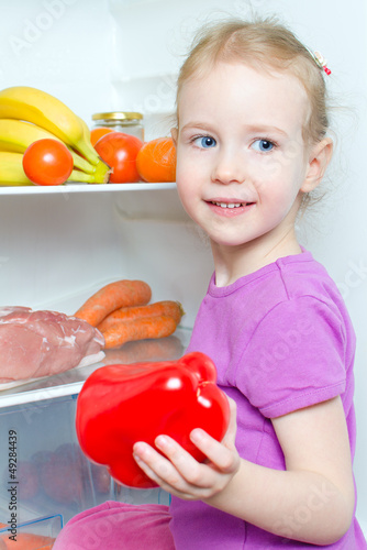 Photo: Happy smiling little girl holding paprika Happy smiling little girl holding paprika