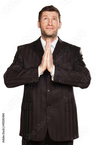 Photo: young businessman praying with his hands set in pray young businessman praying with his hands set in pray
