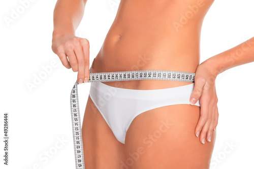 Photo: fit young woman measuring her waistline, white background fit young woman measuring her waistline, white background