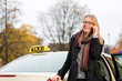 Photo: Young woman in front of taxi with phone Young woman in front of taxi with phone