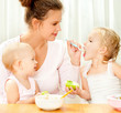 young mother feeding her two daughters from a spoon