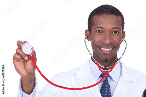 Photo: Smiling doctor holding aloft his stethoscope Smiling doctor holding aloft his stethoscope