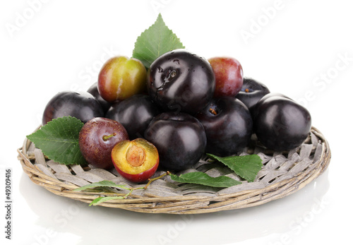 Photo: Rip plums on the wicker cradle isolated on white Rip plums on the wicker cradle isolated on white