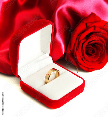 Photo: Beautiful box with wedding ring and rose on red silk background Beautiful box with wedding ring and rose on red silk background