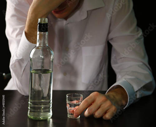Photo: Man with bottle of alcohol, on black background Man with bottle of alcohol, on black background