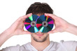 Young man holding compact discs to his face