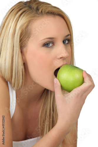Photo: Young woman biting into a crisp green apple Young woman biting into a crisp green apple