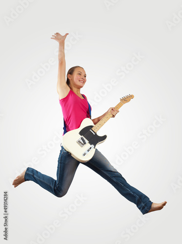 Photo: young woman playing on electro guitar and jumping young woman playing on electro guitar and jumping