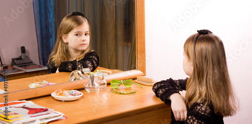Photo: Little girl looking at herself in a mirror Little girl looking at herself in a mirror