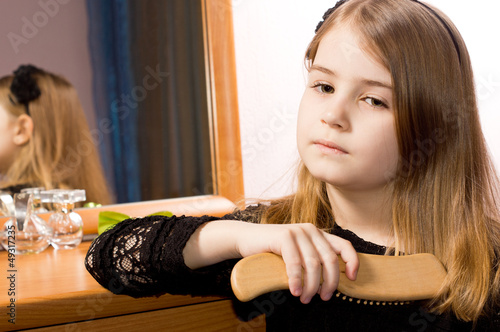 Photo: Sad little girl brushing her hair Sad little girl brushing her hair