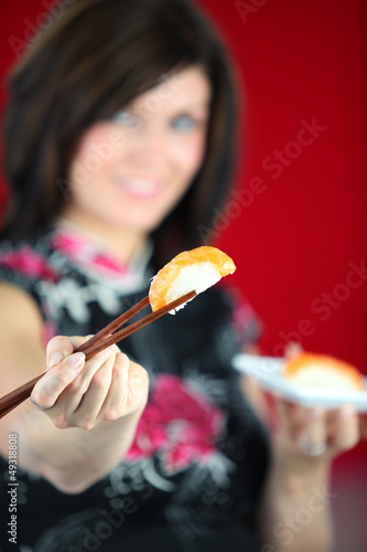 Photo: Woman eating sushi with chopsticks Woman eating sushi with chopsticks