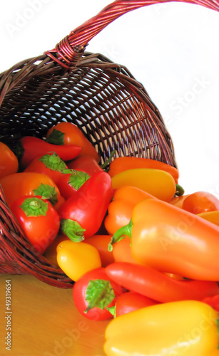 Photo: Basket Full of Colorful Peppers Spilling Out onto a Table Basket Full of Colorful Peppers Spilling Out onto a Table